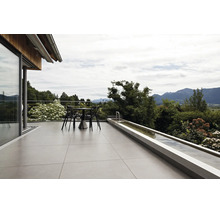 Terrasse moderne avec de grands carreaux de sol, un salon de jardin et un bassin allongé avec vue sur les Alpes.