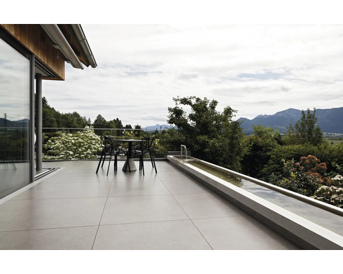 Terrasse moderne avec de grands carreaux de sol, un salon de jardin et un bassin allongé avec vue sur les Alpes.