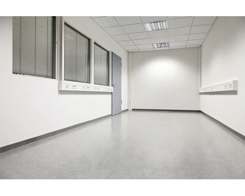 Bureau ou espace commercial vide et fonctionnel avec murs blancs, sol gris, faux plafond et fenêtres avec stores.
