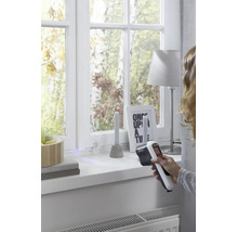 Personne utilisant un détecteur thermique Black et Decker pour vérifier l'isolation des fenêtres dans une pièce lumineuse.