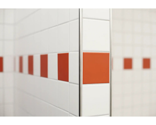 Carrelage mural avec carreaux décoratifs sur un mur de salle de bain avec un profilé métallique pour la protection des coins.