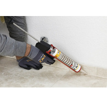 Une personne applique du silicone PCI avec un pistolet à cartouche sur un raccord mural à l intérieur.