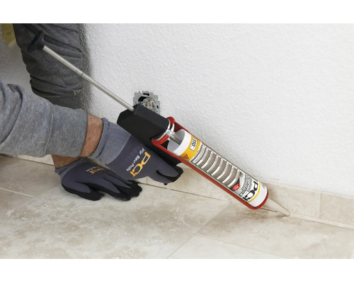 Une personne applique du silicone PCI avec un pistolet à cartouche sur un raccord mural à l intérieur.