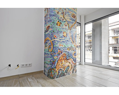 Une colonne ronde avec une mosaïque de verre colorée représentant des motifs sous-marins dans une pièce moderne avec carrelage et grandes baies.