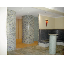 Espace bien-être avec cabines de douche rondes en mosaïque et banc avec surface en mosaïque et éclairage indirect.