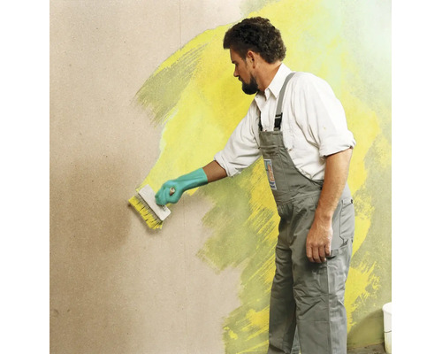 Un artisan peint un mur avec une brosse à encoller et de la peinture murale à l intérieur.