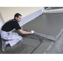 Handwerker glättet frischen Estrichboden auf einer Terrasse mit einer Abziehlatte aus Metall.