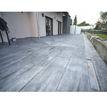 Terrasse avec dalles grand format aspect pierre et caniveau de drainage intégré devant une façade moderne