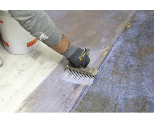 Hand eines Handwerkers beim Auftragen einer Grundierung auf einen Boden mit einem Flächenstreicher.