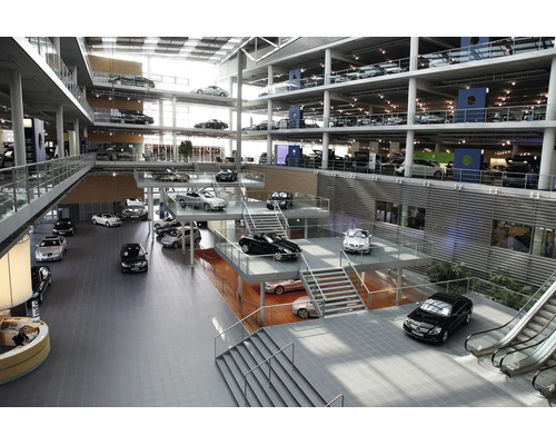 Weitlaeufiges Autohaus mit mehreren Ebenen, Glasfassade und zahlreichen ausgestellten Fahrzeugen in einer modernen Architektur.