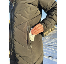 Une personne porte une veste d hiver matelassée et insère un coussin chauffant Thermopad dans la poche zippée.