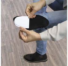 Une personne colle un coussinet chauffant blanc sur une chaussette noire