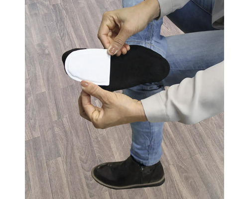 Une personne colle un coussinet chauffant blanc sur une chaussette noire
