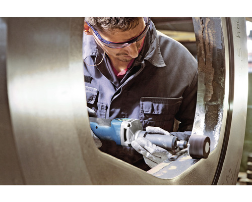 Ein Mann verwendet eine Schleifmaschine an einem Metallstück.