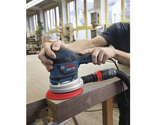 Une personne ponce du bois avec une ponceuse excentrique de Bosch.