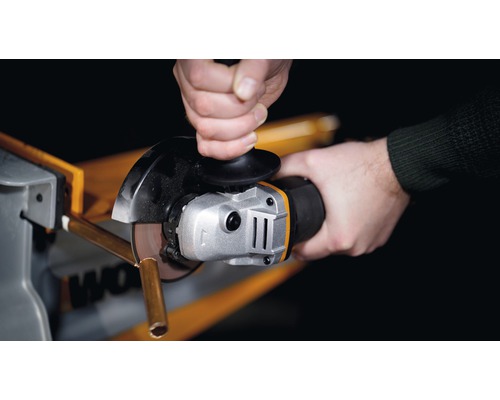 Gros plan d''une personne coupant un tube métallique avec une meuleuse d''angle.