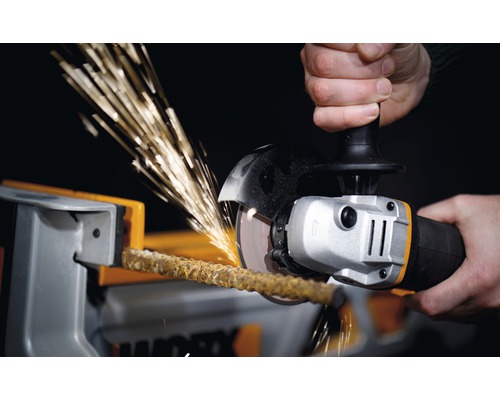 Une personne coupe une barre dans un étau avec une meuleuse d''angle, créant des étincelles.