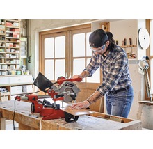 Mann arbeitet mit einer Einhell Kappzugsäge an einem Werkstück in einer Werkstatt.