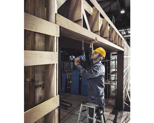 Artisan perçant un trou dans une structure en bois avec une perceuse-visseuse sans fil.