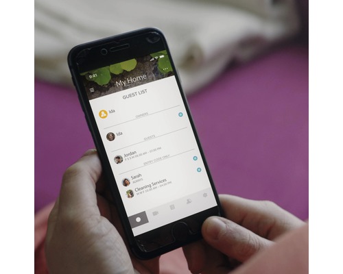 Eine Person hält ein Smartphone mit einer App zur Gästelistenverwaltung in der Hand.