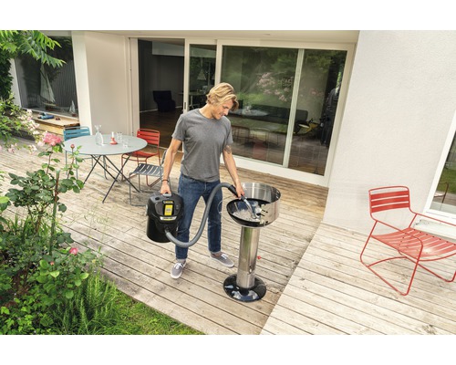 Mann reinigt Grill mit Aschesauger im Außenbereich