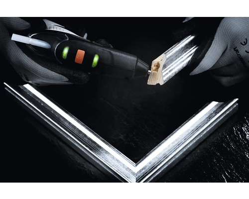 Une personne colle un cadre photo avec un pistolet à colle chaude.