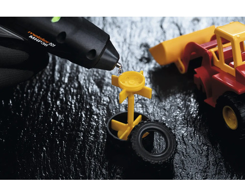 Pistolet à colle chaude collant une pièce de jouet jaune sur une voiture jouet.