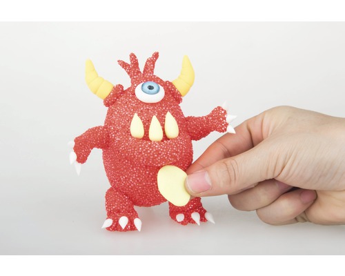 Monstre rouge avec un œil, des cornes et des dents tenu par une main