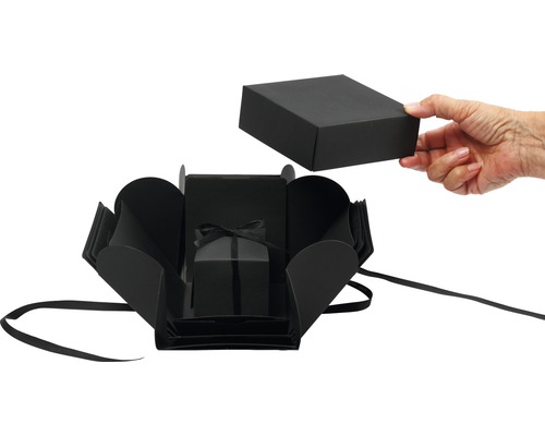 Boîte cadeau noire ouverte avec un ruban et un couvercle tenu par une main