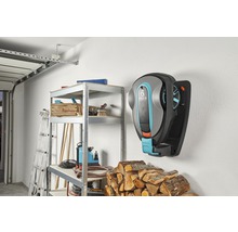 Scène d''un garage avec un robot tondeuse Gardena au mur, une étagère et du bois