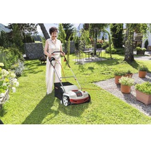 Une femme utilise une tondeuse à gazon dans le jardin.
