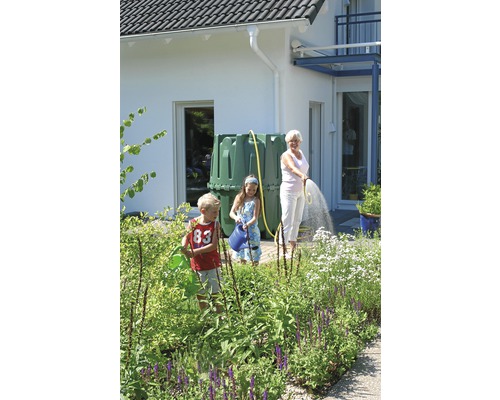 Gartenbewässerung mit Regenwassertank und Familie im Garten vor einem Wohnhaus