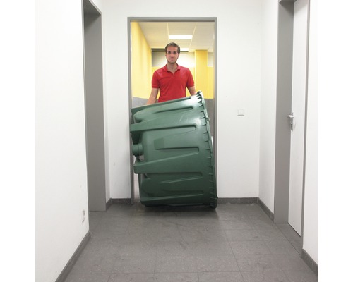 Eine Person transportiert einen grünen Kompostbehälter durch einen Flur