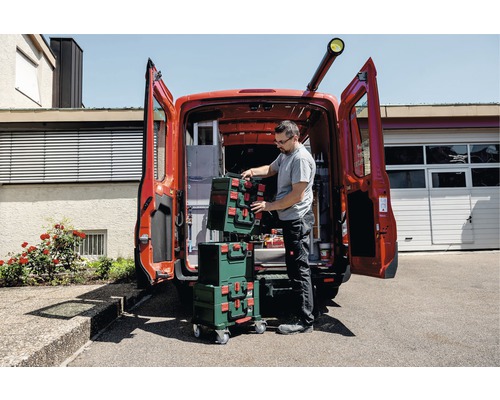Handwerker ordnet Werkzeugkoffer im Lieferwagen. Mobile Werkstattlösung für Baustellen.