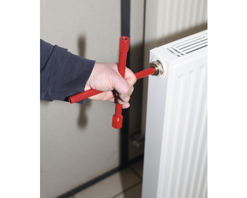 Eine Person benutzt einen Heizkörperschlüssel zum Entlüften eines Heizkörpers.