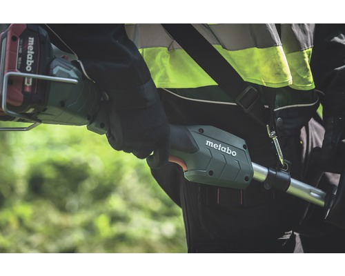 Eine Person trägt eine Metabo Akku-Motorsense über der Schulter.
