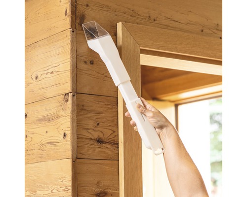 Hand, die ein weisses Staubentfernungswerkzeug an einem Holzrahmen verwendet