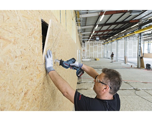 Mann schneidet mit einer Akku-Säbelsäge ein Loch in eine Holzplatte.