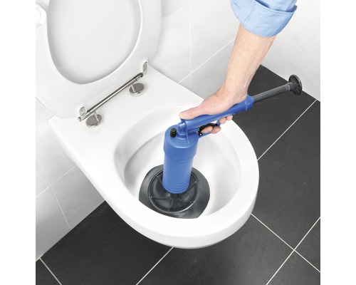 Hand betätigt einen Pümpel in einer Toilette, um eine Verstopfung zu lösen.