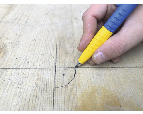 Une personne trace une ligne sur une planche de bois avec un crayon de charpentier.