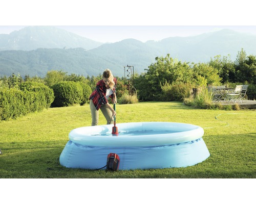 Frau benutzt eine Poolpumpe, um Wasser aus einem aufblasbaren Pool im Garten zu entfernen.