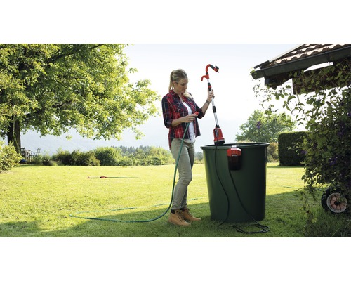 Frau bedient eine Teleskop-Gartenbrause zum Bewässern von Pflanzen im Garten.