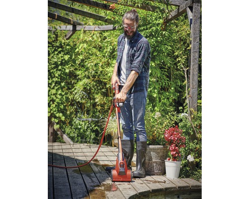 Mann reinigt Holzterrasse mit Terrassenreiniger im Garten