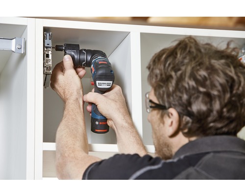 Une personne fixe une porte de meuble à une armoire à l''aide d''une visseuse sans fil.