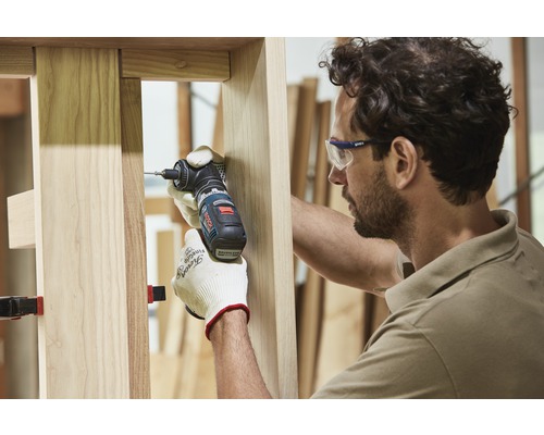 Un artisan travaille avec une visseuse d''angle sur un cadre en bois.