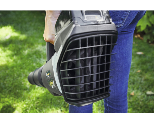 Eine Person hält einen Laubbläser im Garten.