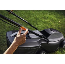 Eine Hand betätigt den Griff eines Rasenmähers.