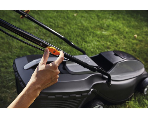 Eine Hand betätigt den Griff eines Rasenmähers.