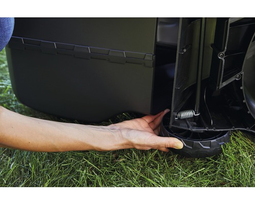 Detailansicht eines Rasenmähers mit Hand an einem Rad zur Höhenverstellung.