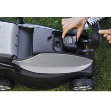 Aufsicht auf einen Rasenmäher mit einer Hand, die einen Akku einsetzt